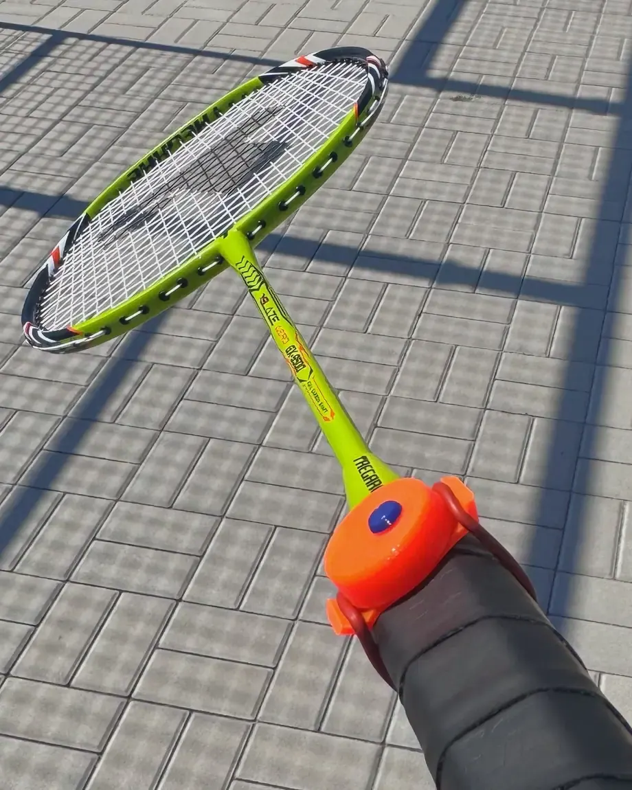 Pohled hráče: palec kliká na klikači DOTTA na badmintonové raketě