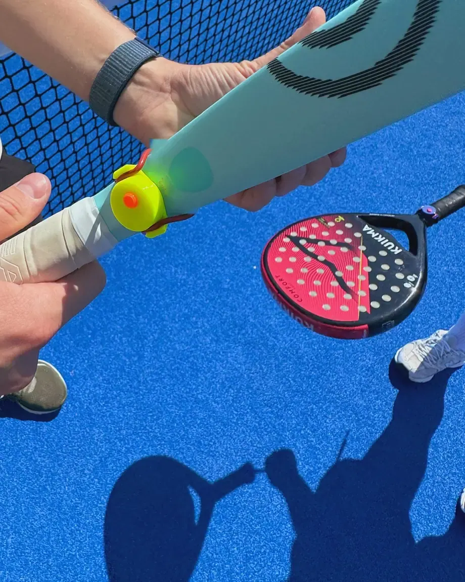 Ruce nasazují klikač DOTTA na grip rakety O-kroužkem